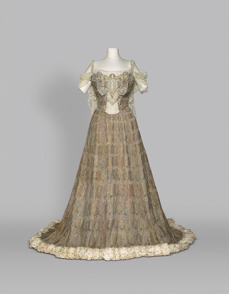 Full length gown embroidered with gold and silver thread to form peacock feathers along the entire skirt, with both on and off the shoulder sleeves and a very ornate bodice.